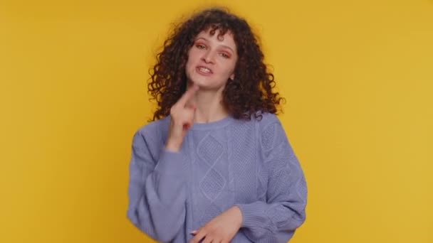 I choose you. Curly haired pretty woman pointing to camera and looking with playful happy expression, making choice, showing direction. Young smiling teen girl isolated on yellow studio background - Materiał filmowy, wideo