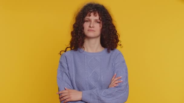 Displeased upset curly haired woman reacting to unpleasant awful idea, dissatisfied with bad quality, wave hand, shake head No, dismiss idea, dont like proposal. Young girl on yellow studio background - Metraje, vídeo