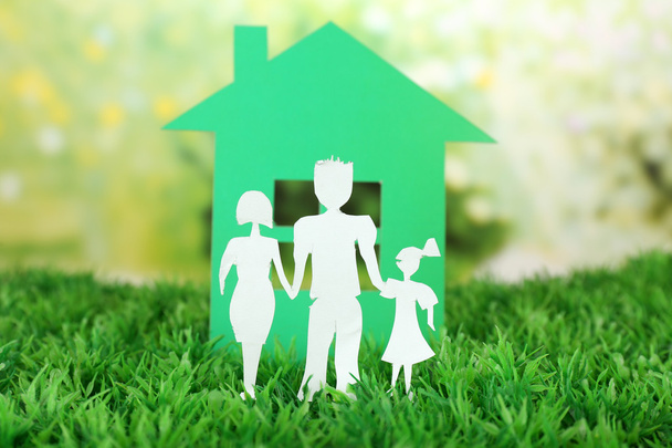 Вирізати паперову сім'ю і будинок на зеленій траві і яскравий розмитий фон
 - Фото, зображення