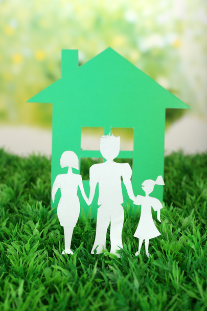 Família de papel de recorte e casa na grama verde e fundo embaçado brilhante
 - Foto, Imagem