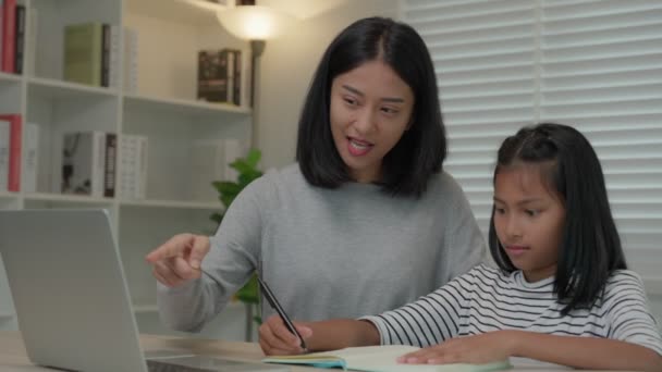 Mother teaching lesson for daughter by laptop. Asian young little girl learn at home. Do homework with kind mother help, encourage for exam. Asia girl happy Homeschool. Mom advise education together. - Séquence, vidéo