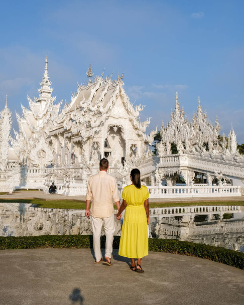 Ένα ζευγάρι επισκέπτεται το Λευκό Ναό Τσιάνγκ Ράι Ταϊλάνδη, Wat Rong Khun, γνωστό και ως Λευκό Ναό, στην Τσιάνγκ Ράι, Ταϊλάνδη. Ασιάτισσες και λευκοί άντρες επισκέπτονται ένα ναό με γαλάζιο ουρανό. - Φωτογραφία, εικόνα