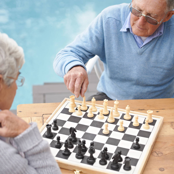Провожу время увлекательной игрой в шахматы. Пожилая пара играет в шахматы - Фото, изображение
