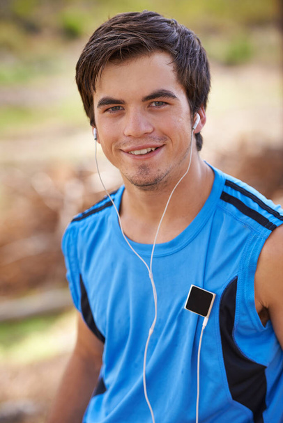 This song gets me hyped. Portrait of a young male runner listening to music on his mp3 player - Photo, Image