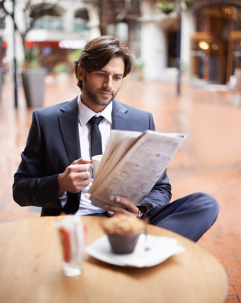 Enjoying his lunch break. A businessman sitting at a street side cafe reading the news - Photo, Image