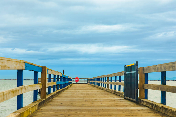 Wooden pier with sea and blue sky at the background. A wooden pier or jetty heading toward the horizon. travel photo, nobody, copy space for text - Photo, Image