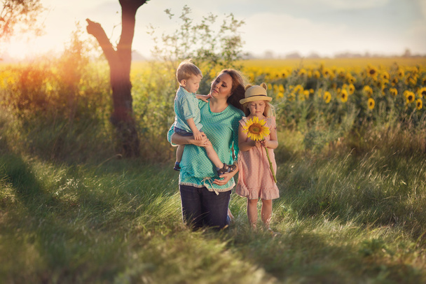 Mother with children in sunflowers - Φωτογραφία, εικόνα
