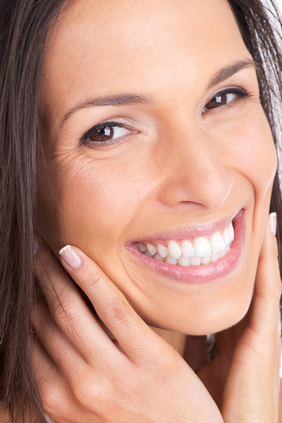 My face feels softer than ever. Closeup shot of a beautiful woman with a radiant smile touching her face - Foto, immagini