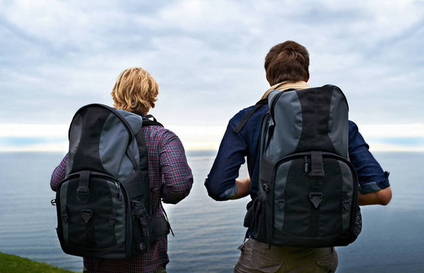 Seeking out the best views. Rear-view of two backpackers admiring a great view - Foto, Imagen