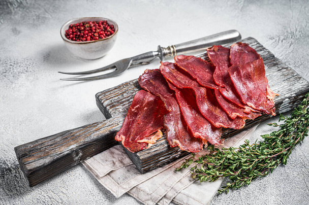 Pastirma Turkish sliced pastrami, dried beef meat with spices on wooden board. White background. Top view. - Photo, Image