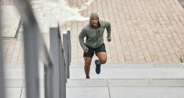 Fitness, runner or black man running on stairs for training, exercise or cardio workout in Chicago. Mission, mindset or healthy athlete in hoodie with motivation or sports goals exercising on steps. - Foto, afbeelding