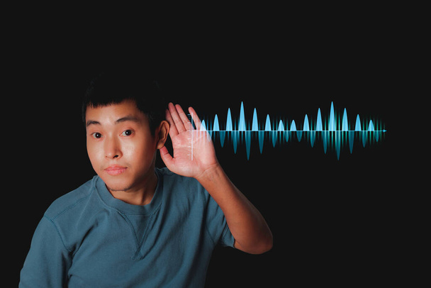 Ο νεαρός ακούει φήμες ή κουτσομπολεύει με ηχητικά κύματα. Τεχνολογία ισοσταθμιστή ήχου. - Φωτογραφία, εικόνα