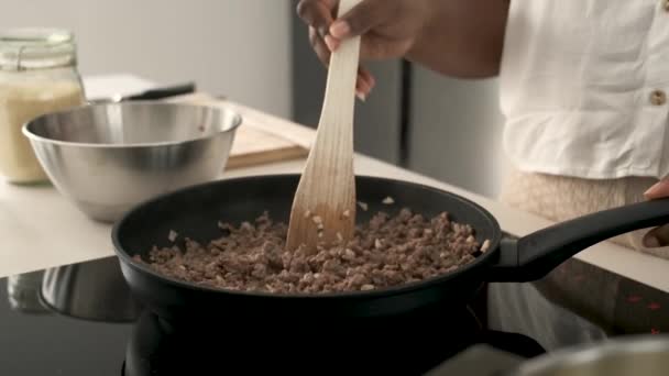 Közelkép a kubai nő kezét főzés darált marhahús és fokhagyma egy serpenyőben, hogy készítsen kubai stílusú töltött burgonya. - Felvétel, videó