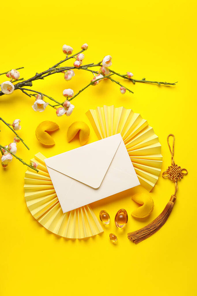Envelope with fortune cookies, sakura and Chinese symbols on yellow background. New Year celebration - Photo, image
