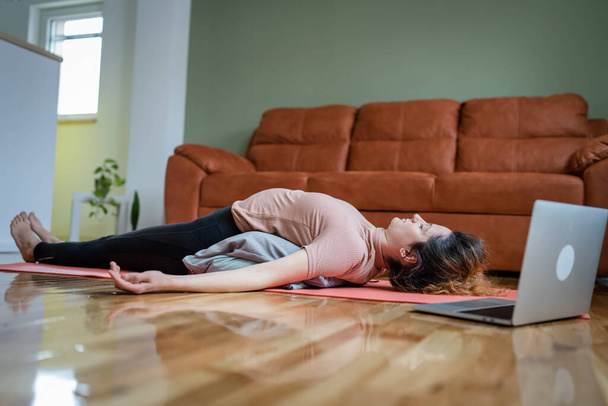 One adult caucasian woman practice restorative yoga at home - Foto, imagen
