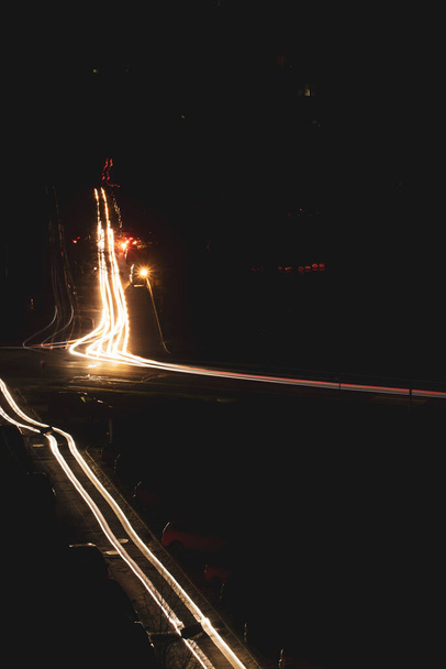 Pimeä kaupunki kadulla yöllä ja auton ajovalot pitkän altistumisen. Pyörtyminen Kiovassa johtuen Venäjän sodasta Ukrainassa. Maailmanlaajuinen sosiaalinen sähköongelma. Pimeys kaupungin yllä. Autot maanteillä. - Valokuva, kuva
