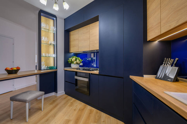 Κομψό μεγάλο μπλε και ξύλινο διαμέρισμα στούντιο με κουζίνα ανοιχτή στο σαλόνι μετά από καλή ανακαίνιση - Φωτογραφία, εικόνα