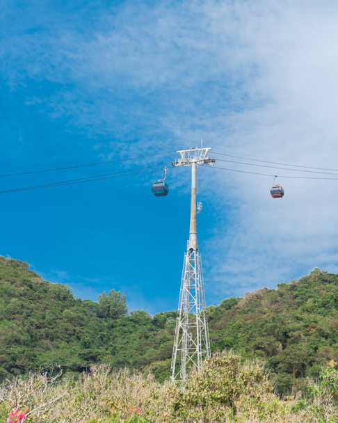 Upward view of gondola lift support tower with cable cars and mountain background in Vung Tau, Vietnam. Steel and tubular framework pylon for aerial tramway to Ho May Park tourist attraction - Fotó, kép