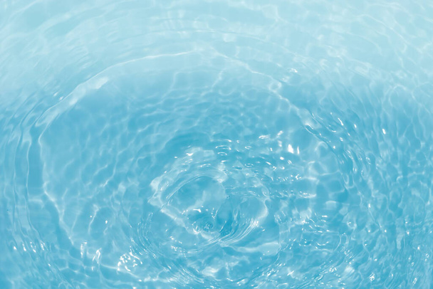 Defocus wazig transparant blauw gekleurd helder kalme water oppervlak textuur met spatten en bellen. Trendy abstracte natuur achtergrond. Watergolven in zonlicht met bijverschijnselen. Blauw water schijnt  - Foto, afbeelding