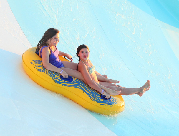two preteen beautiful girl on water slide in open air water park - Photo, Image