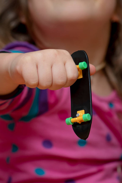The girl holds a Fingerboard in her hand, close-up, selective focus. - Foto, Bild