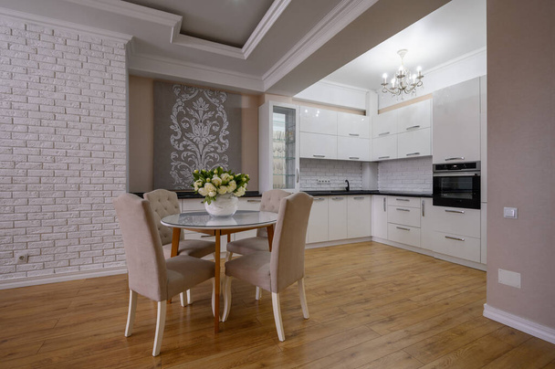 Luksusowa biała nowoczesna kuchnia z różowymi i białymi ścianami i laminowaną podłogą drewnianą w studio apartamencie - Zdjęcie, obraz