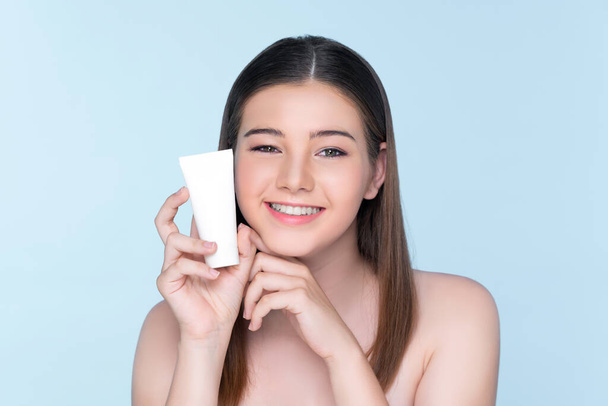 Young charming girl with natural beauty, perfect smooth skin hold lotion, cream, moisturizer tube. Beautiful girl show skincare product smiling on isolated background. - Fotoğraf, Görsel