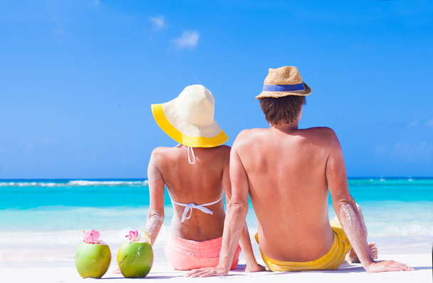 vue arrière du couple assis sur la plage tropicale avec deux cocktails de noix de coco frais
 - Photo, image