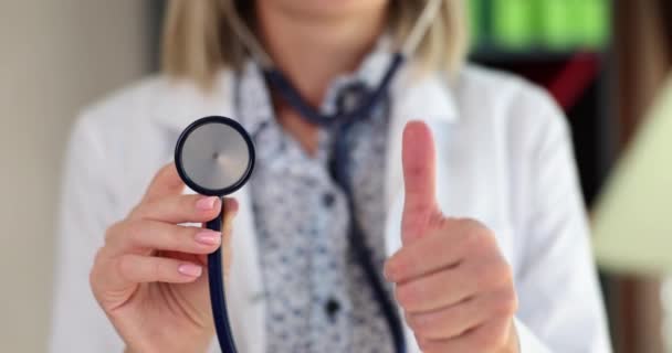 Doctor hand with thumbs up holds stethoscope. Recommendations for quality medical services and insurance - Materiał filmowy, wideo