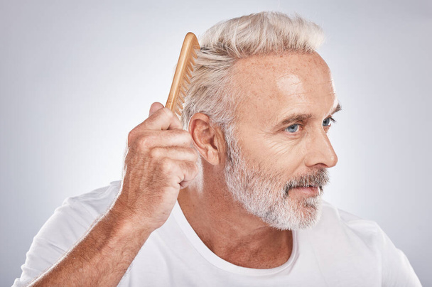 Senior man, hair comb and brush on studio background for beauty, barber salon and cosmetics. Face of male model, brushing hairstyle and fashion for manly grooming, hair care and fresh morning routine. - 写真・画像