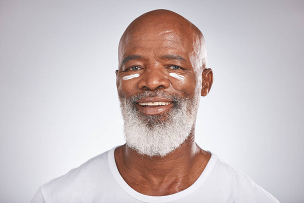 Facial cream, beauty and skincare of senior man in studio for self care with dermatology and cosmetics product on skin. Portrait of happy black male with sunscreen or lotion for glow and moisturizer. - Foto, afbeelding