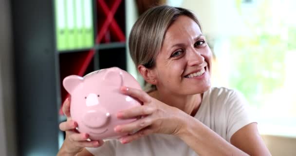 Save money and piggy bank in hands of smiling woman. Investment finance concept of lending deposits of wealth and savings - Materiał filmowy, wideo