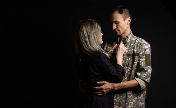 militair man en zijn vrouw op een zwarte achtergrond. - Foto, afbeelding