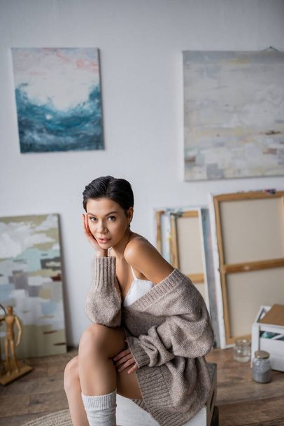 Short haired sexy artist looking at camera while sitting in workshop  - Photo, image