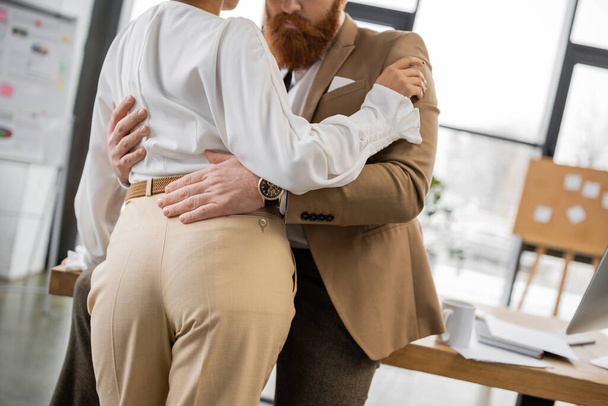 cropped view of bearded man hugging african american colleague in office  - Foto, Imagem