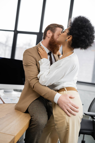 アフリカ系アメリカ人女性の尻に触れる髭のビジネスマン  - 写真・画像