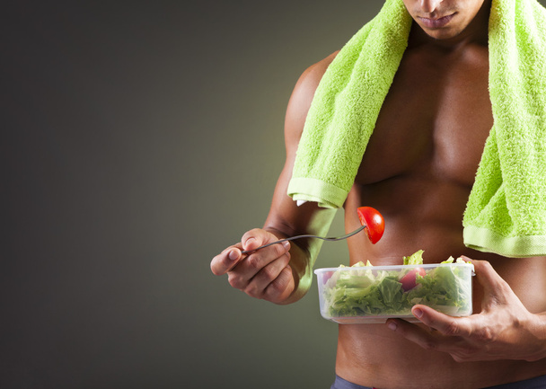 Strong man holding a bowl of fresh salad - Fotó, kép