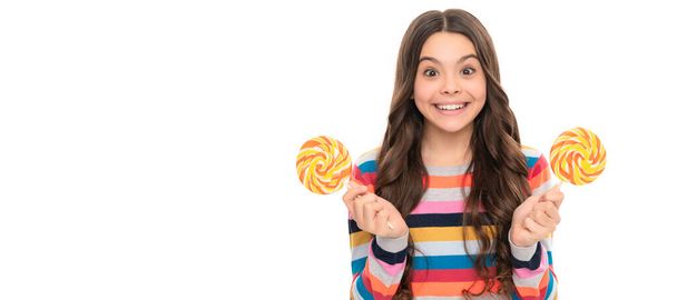 удивленный ребенок в красочном свитере с леденец конфеты на палочке изолированы на белом фоне, сладкая жизнь. - Фото, изображение