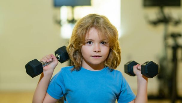 Kid raising a dumbbell. Cute child training with dumbbells. Kids fitness. Child workout kid in gym. Kid boy exercising with dumbbells. Healthy kids - Foto, immagini