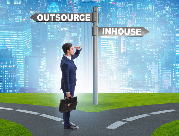 Businessman at crossroads deciding between outsourcing and inhouse - Photo, Image