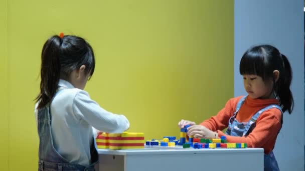 Cute girls playing with lego blocks at home. Child playing and building with colorful plastic bricks table. - Filmagem, Vídeo