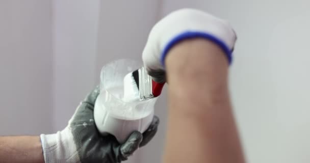 Brush dipped in can of white paint and preparation for painting walls. Home renovation and paint selection - Video, Çekim