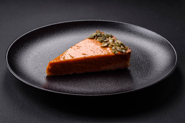Beautiful tasty pumpkin pie with slices on a black ceramic plate on a dark concrete background - Foto, immagini