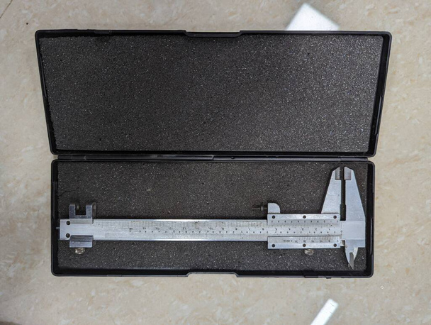 a brand new stainless steel analog vernier caliper scale tool used for precision measurements placed in a box isolated - Foto, immagini