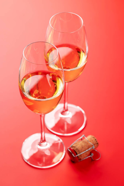 Открытка на день Святого Валентина с двумя бокалами шампанского и пробка от шампанского. На красном фоне с пространством для приветствий - Фото, изображение