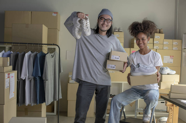 Confident mixed race young couple of Asian man and african-american woman retail seller, entrepreneur, online store drop shipping small business owner looking at camera in delivery shipping warehouse - Foto, Imagen