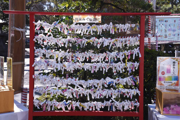  Playing 'Omikuji' at a Japanese shrine. Omikuji is a written fortune-telling about the person's near future on a slip of paper. - Foto, Imagen