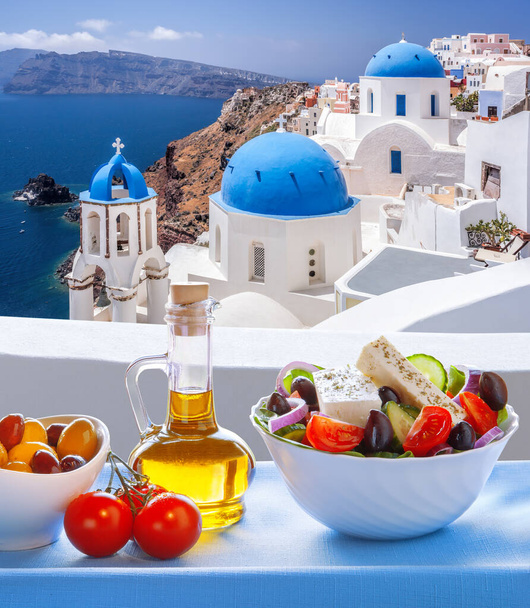 Greek food against famous churches in Oia village on Santorini island in Greece - Foto, Imagem