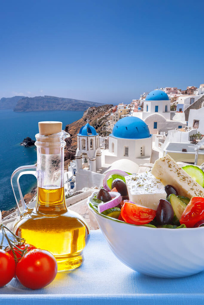 Greek food against famous churches in Oia village on Santorini island in Greece - Foto, Bild