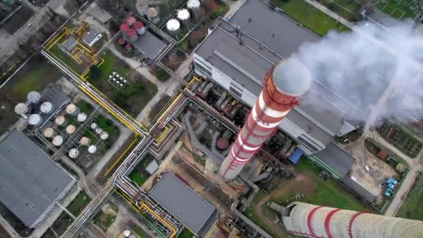 Aerial drone vertical view of thermal power plant in Chisinau at cloudy weather, Moldova. View of pipes with felling steam, moving cars and bare trees around - Felvétel, videó